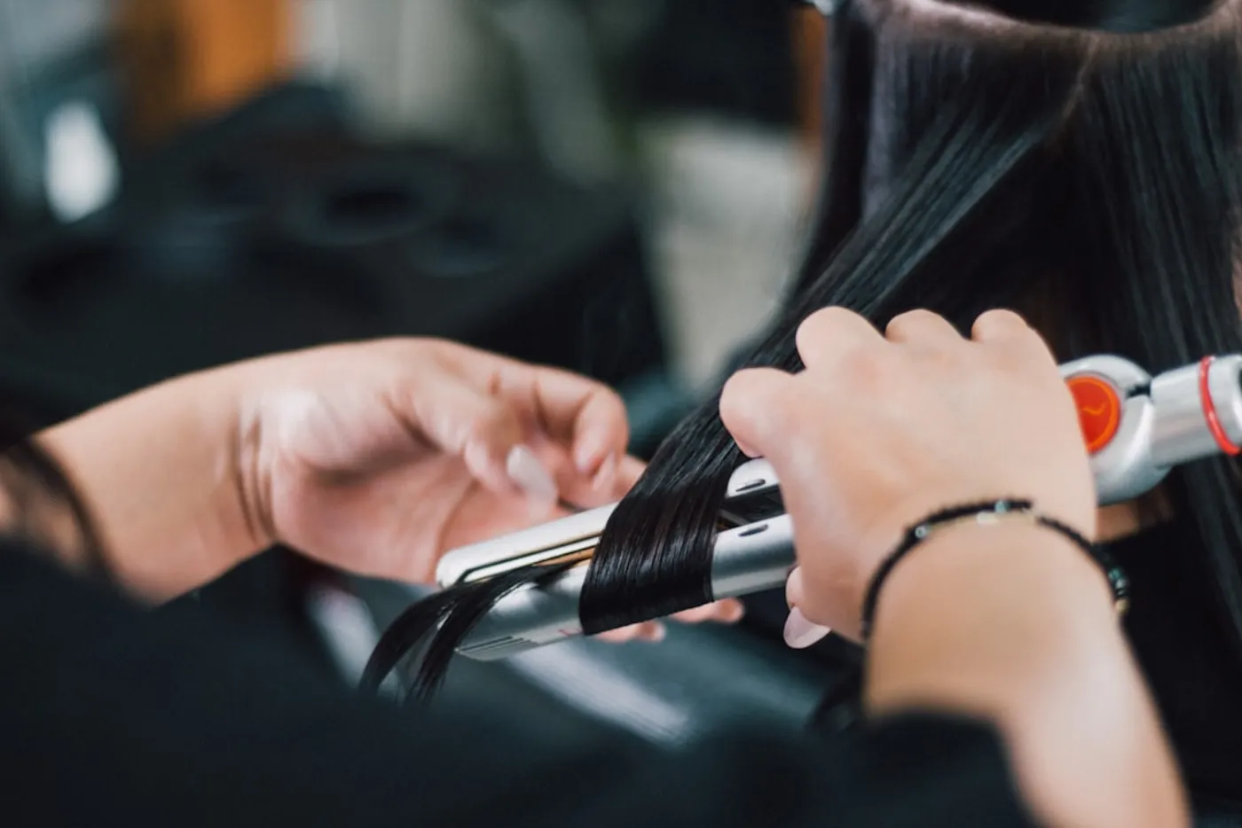 Expert hairstylist blow drying glossy hair in salon