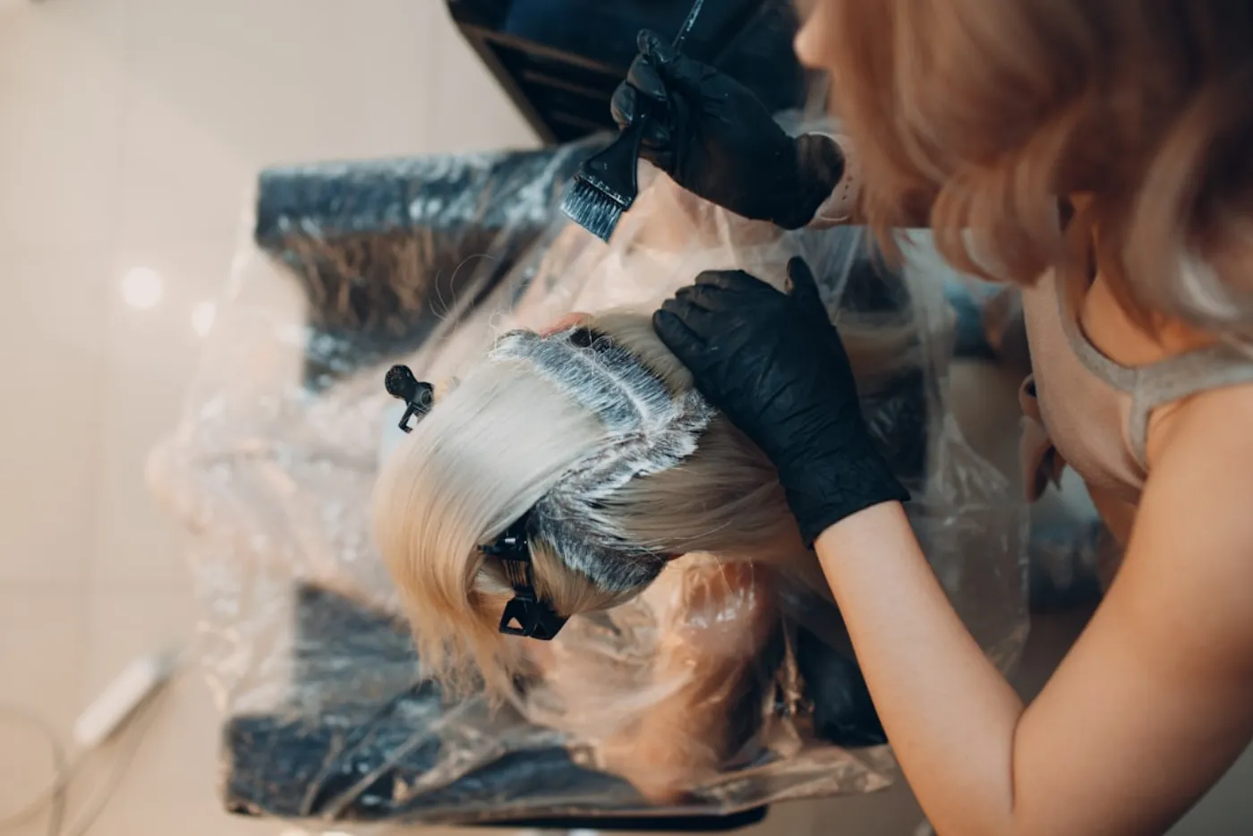A professional hairstylist carefully applying a protective toner to a client's hair