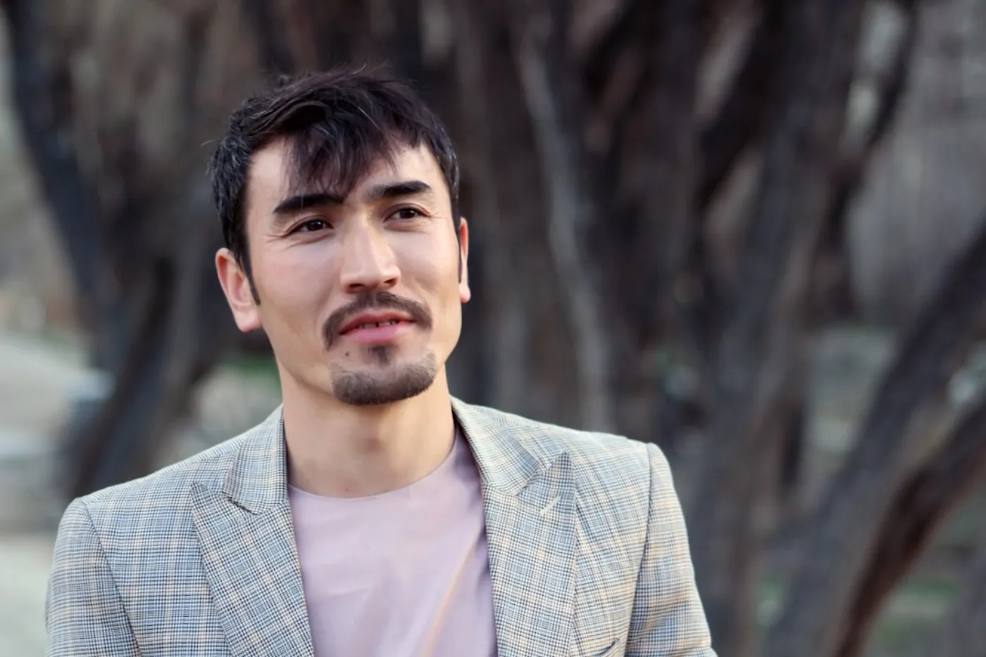 A confident man with a modern hairstyle and well-groomed beard.