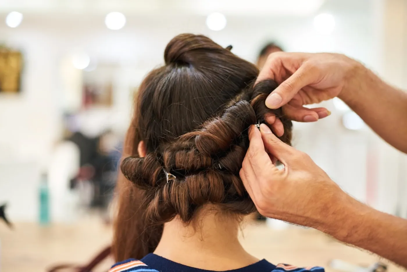 Stylist applying precise balayage colour in a modern salon mirror