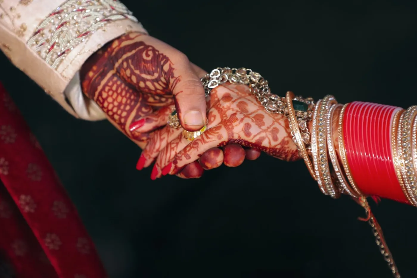 Close-up of a newlywed couple's hands, showing perfectly manicured nails and wedding rings