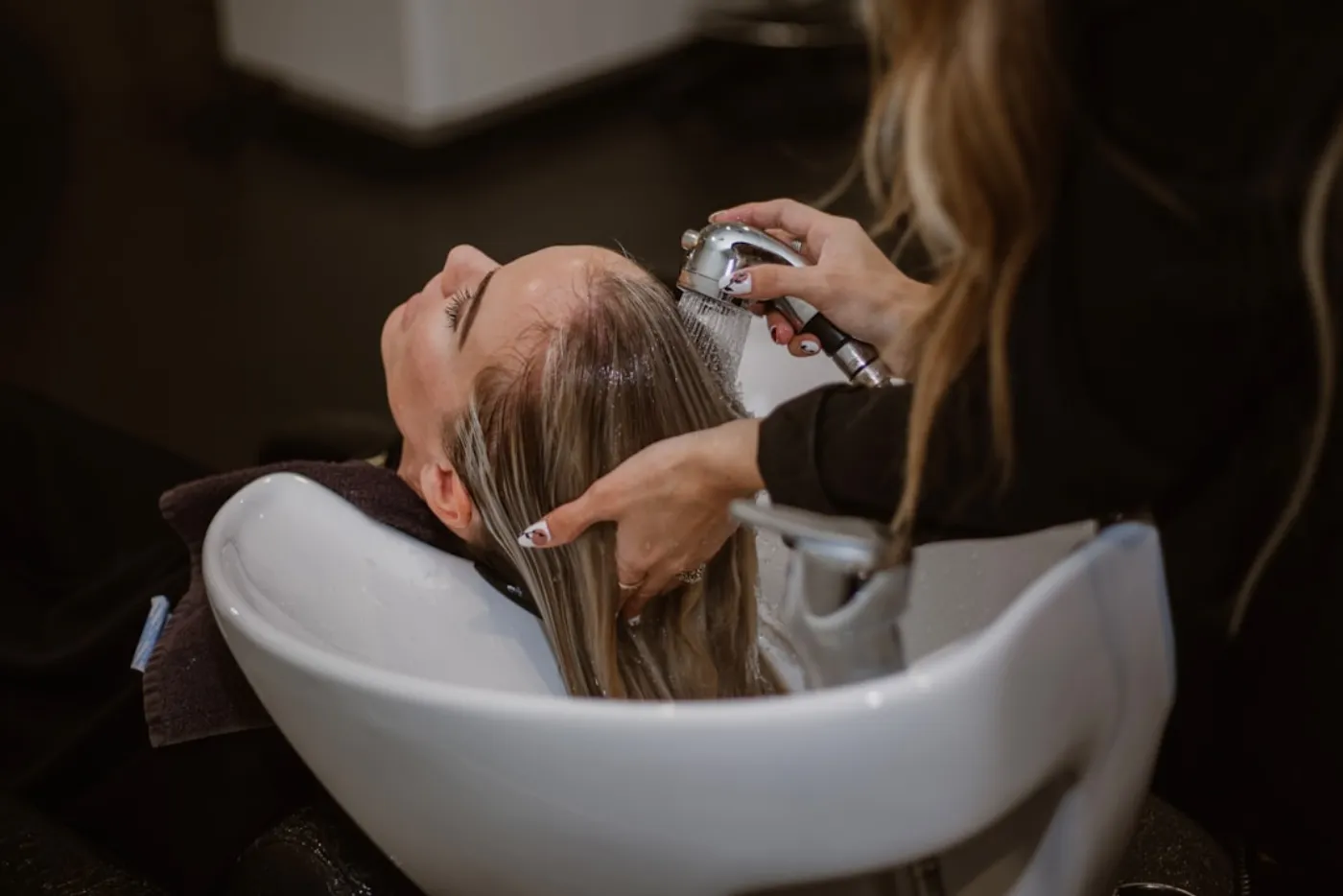 A woman with beautifully styled, sun-kissed balayage hair, reflecting a summer look, in a premium salon setting.