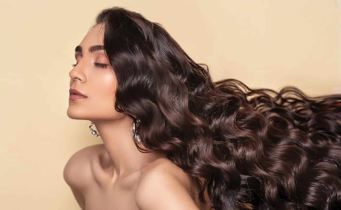 A woman showcasing a rich, deep brown hair colour, perfect for the autumn and winter seasons, styled beautifully in a salon.