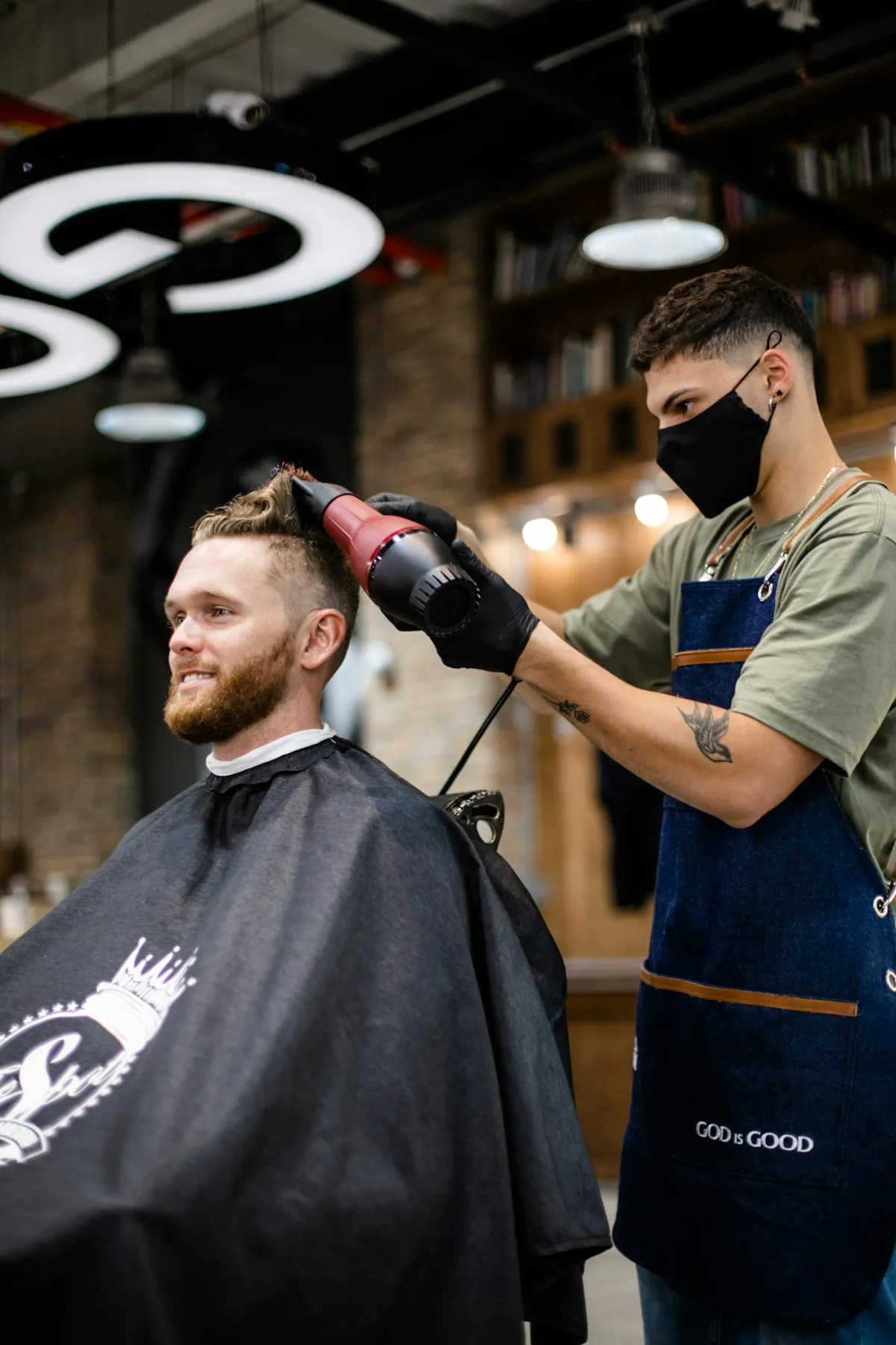 A barber blow-drying and styling a man's hair in a professional studio