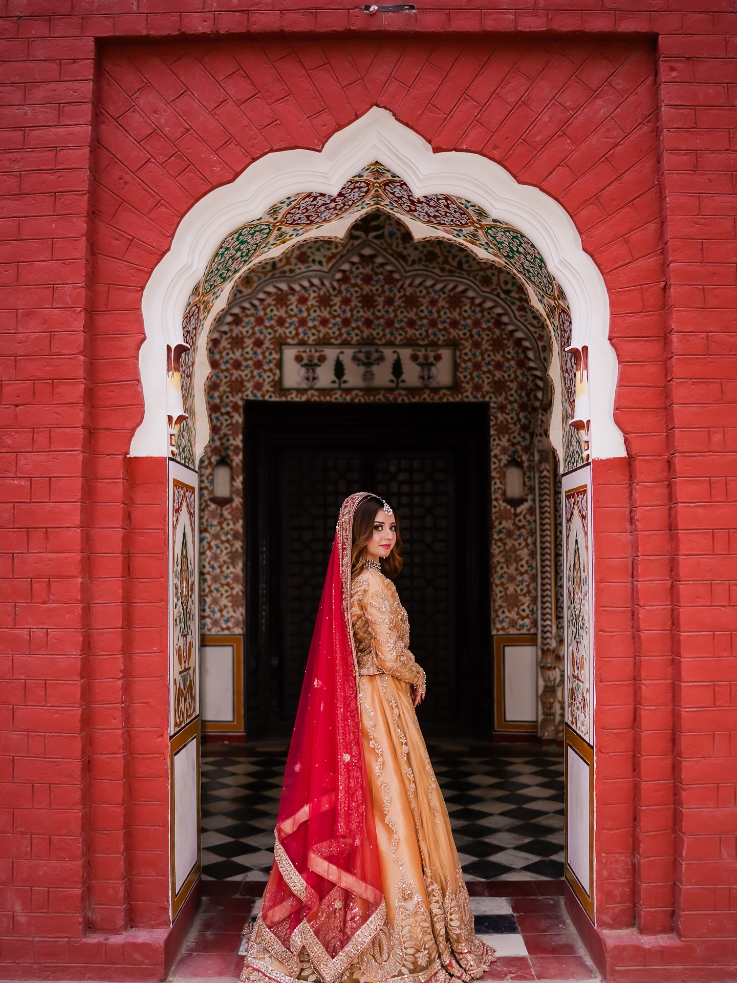 Bridal portrait in a red archway doorway by House of Salons
