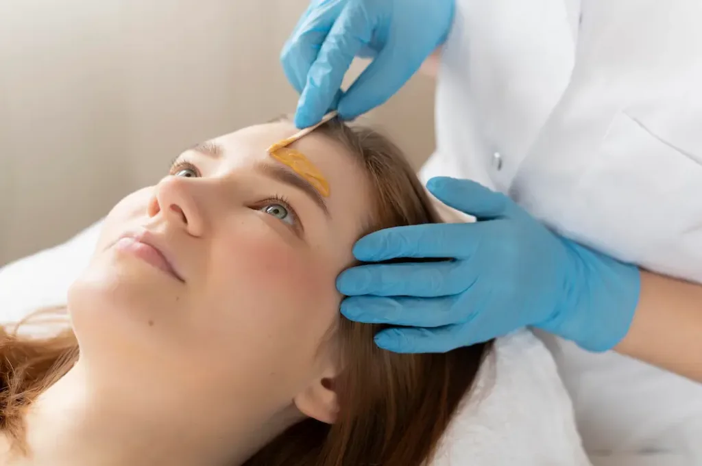 young woman getting waxing facial